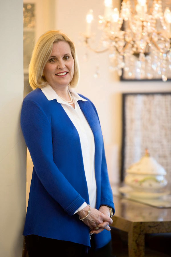 woman blue sweater leaning against wall smiling with hands front brenda shute is a dallas texas decorator and stager contact call Brenda